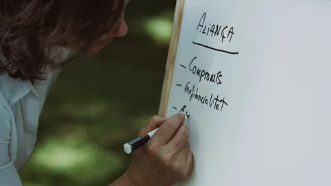 La Pau escriu en una pissarra blanca sota el títol «Aliança» les paraules «Compromís» i «Confidencialitat».